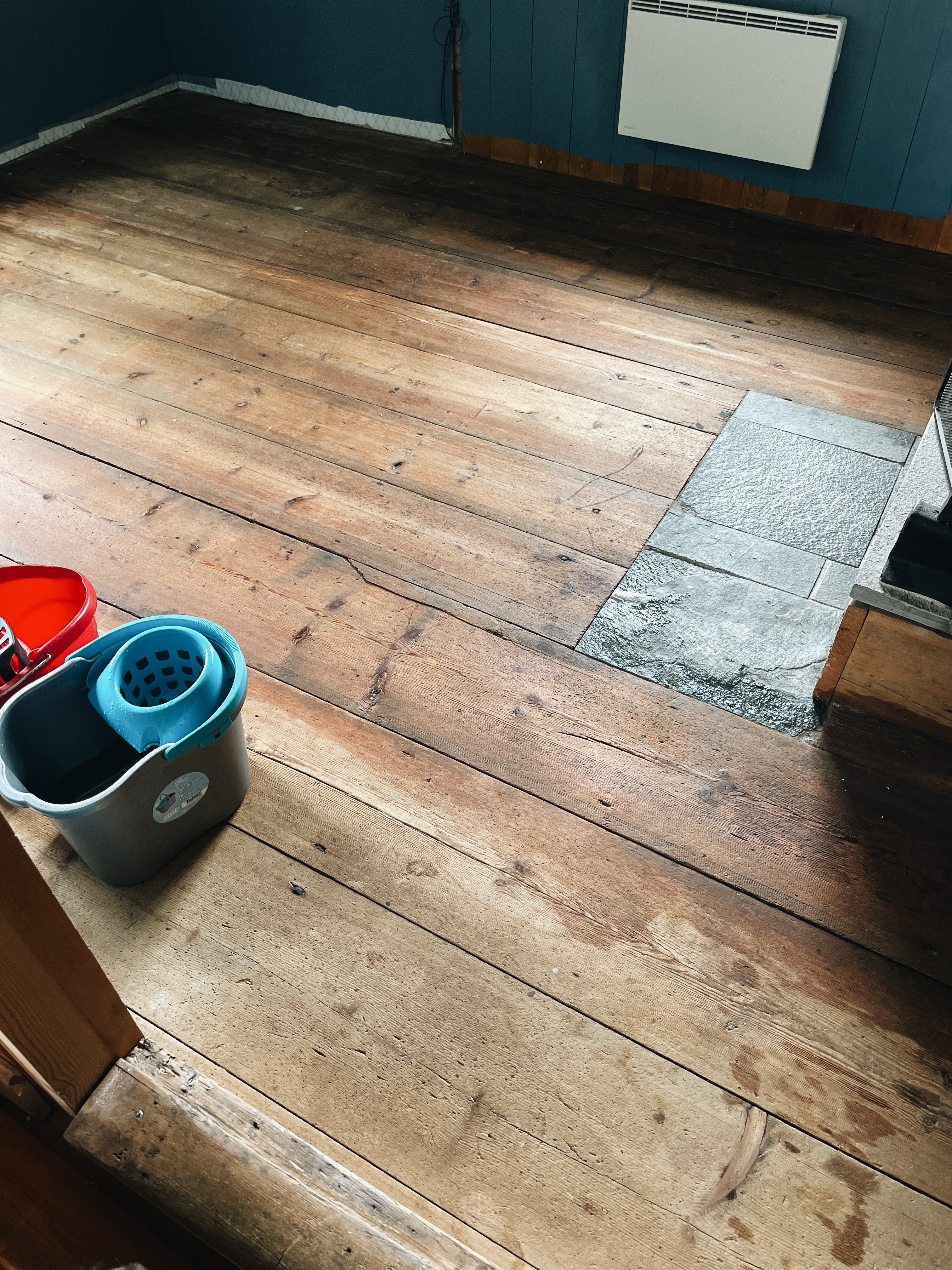 Kökets breda golvplankor med stentröskel vid spisen